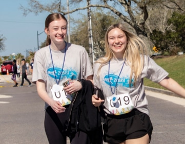 Two women running and smiling at the Zebra Run